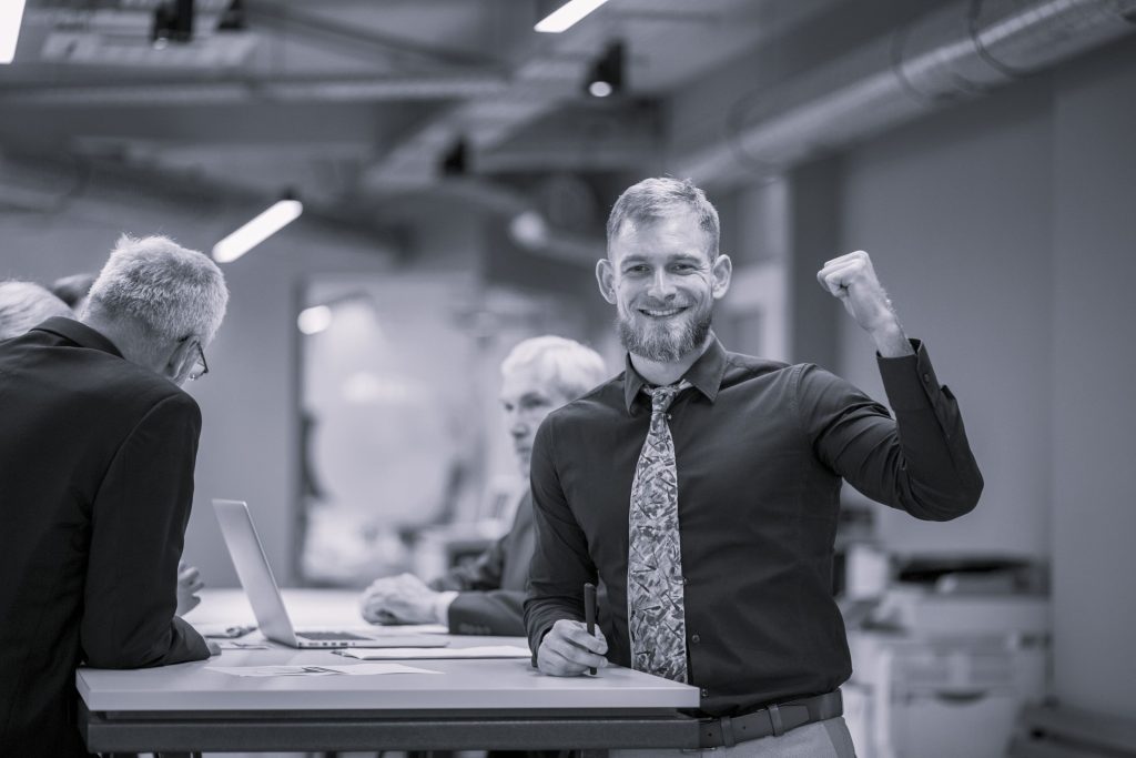 Mann mit Bart hebt Hand Freude wie nach Vertragsabschluss