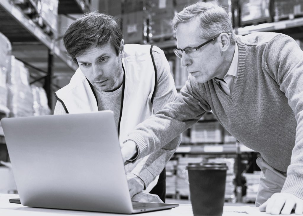 2 Männer vor Laptop in einem Lager